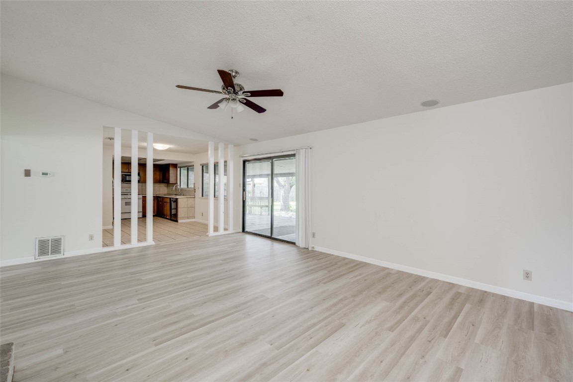 1402 Meadgreen Circle Austin, TX 78758 - Photo 5 of 35 Unfurnished living room with light wood-style floors, a ceiling fan, and lofted ceiling