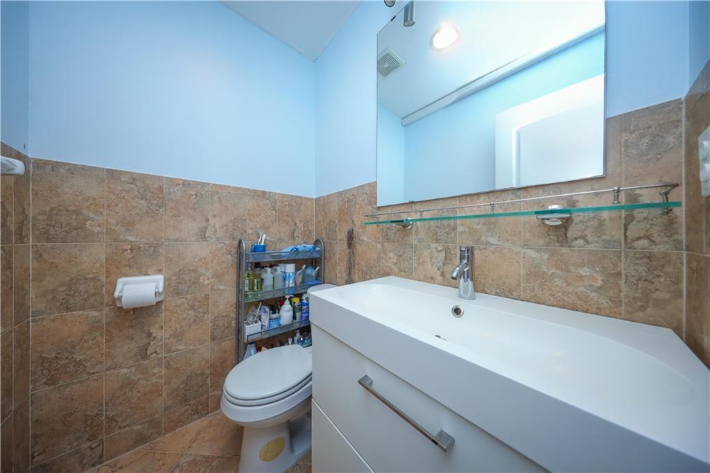 8657 Bay 16th Street, Unit 3B Brooklyn, NY 11214 - Photo 6 of 17 a bathroom with a sink a toilet and a mirror