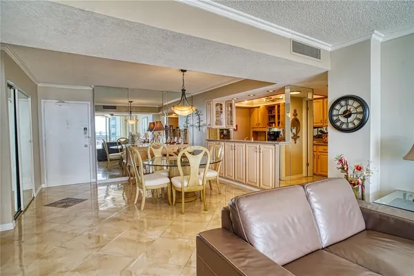 a living room with couches a dining table and kitchen view with wooden floor