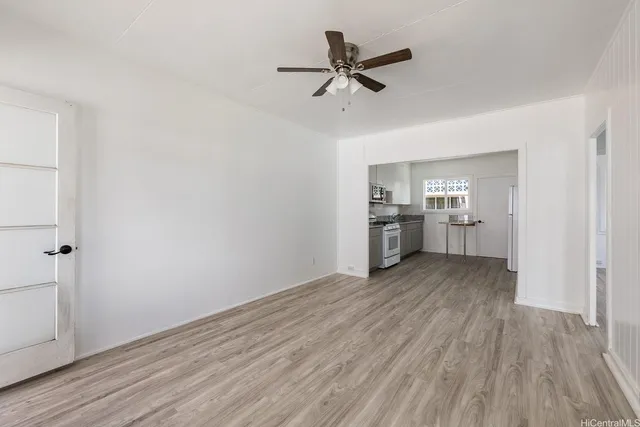 a view of a kitchen with wooden floor a ceiling fan and windows