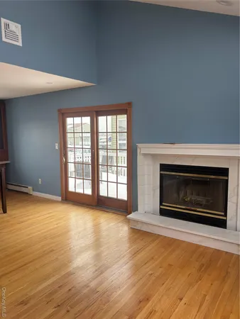 an empty room with wooden floor fireplace and windows