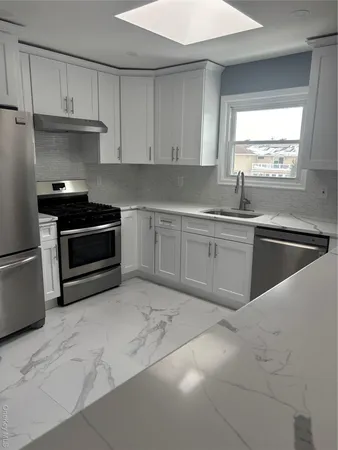 a kitchen with granite countertop a sink stainless steel appliances and window