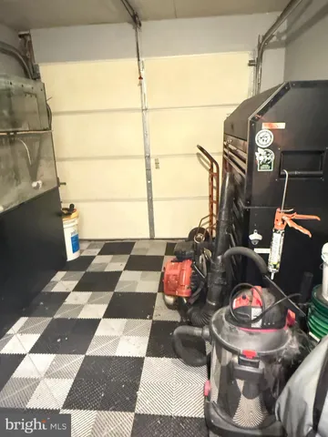 a living room with a black white checkered floor with a gaming machine and dining table