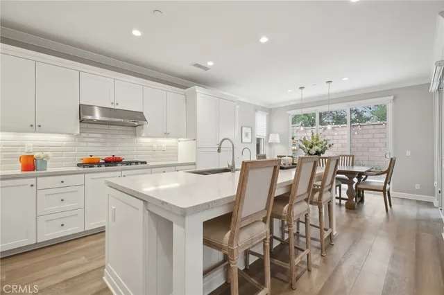 a kitchen with stainless steel appliances granite countertop a kitchen island a stove a table and a refrigerator