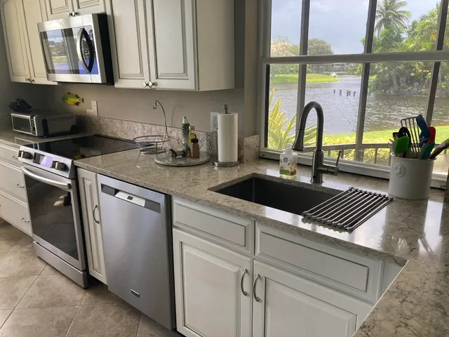 a kitchen with stainless steel appliances granite countertop a sink a counter space and a window