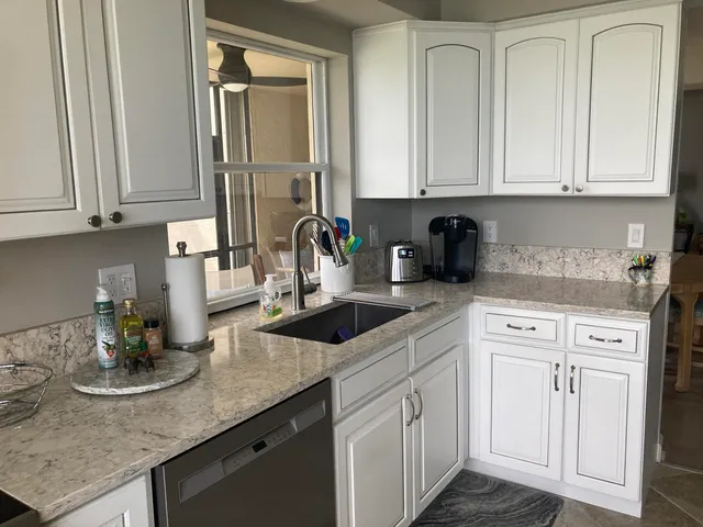 a kitchen with white cabinets and sink