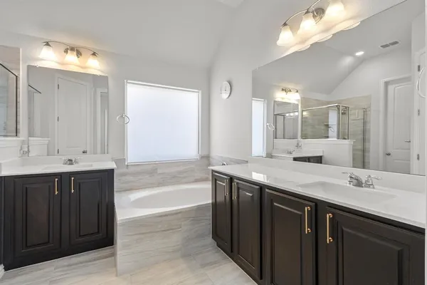 a spacious bathroom with a granite countertop double vanity sink a mirror and a bathtub