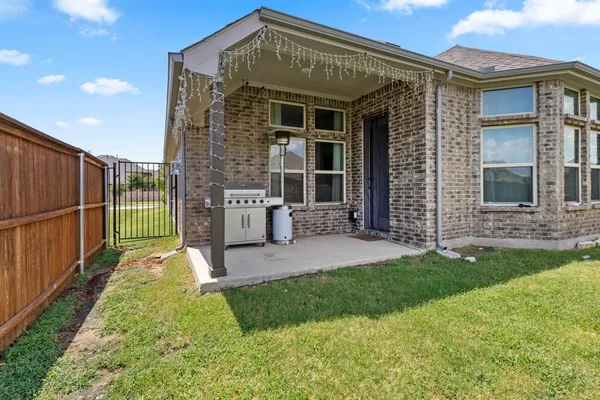 a view of a house with brick walls and a yard with a large tree