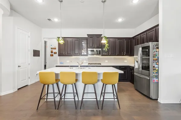 a kitchen with stainless steel appliances kitchen island granite countertop refrigerator and cabinets