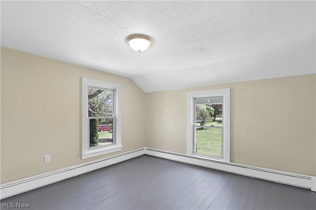 2926 Burns Road Madison, OH 44057 - Photo 26 of 37 Empty room with hardwood / wood-style flooring, a healthy amount of sunlight, a textured ceiling, and vaulted ceiling