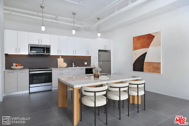 a kitchen with stainless steel appliances a stove a sink a microwave a dining table and chairs