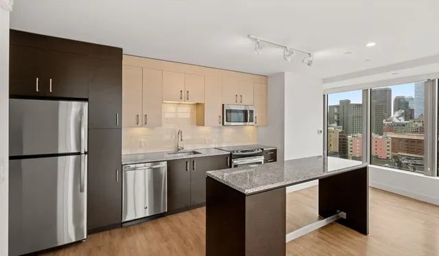 a kitchen with stainless steel appliances granite countertop a refrigerator a sink and a stove