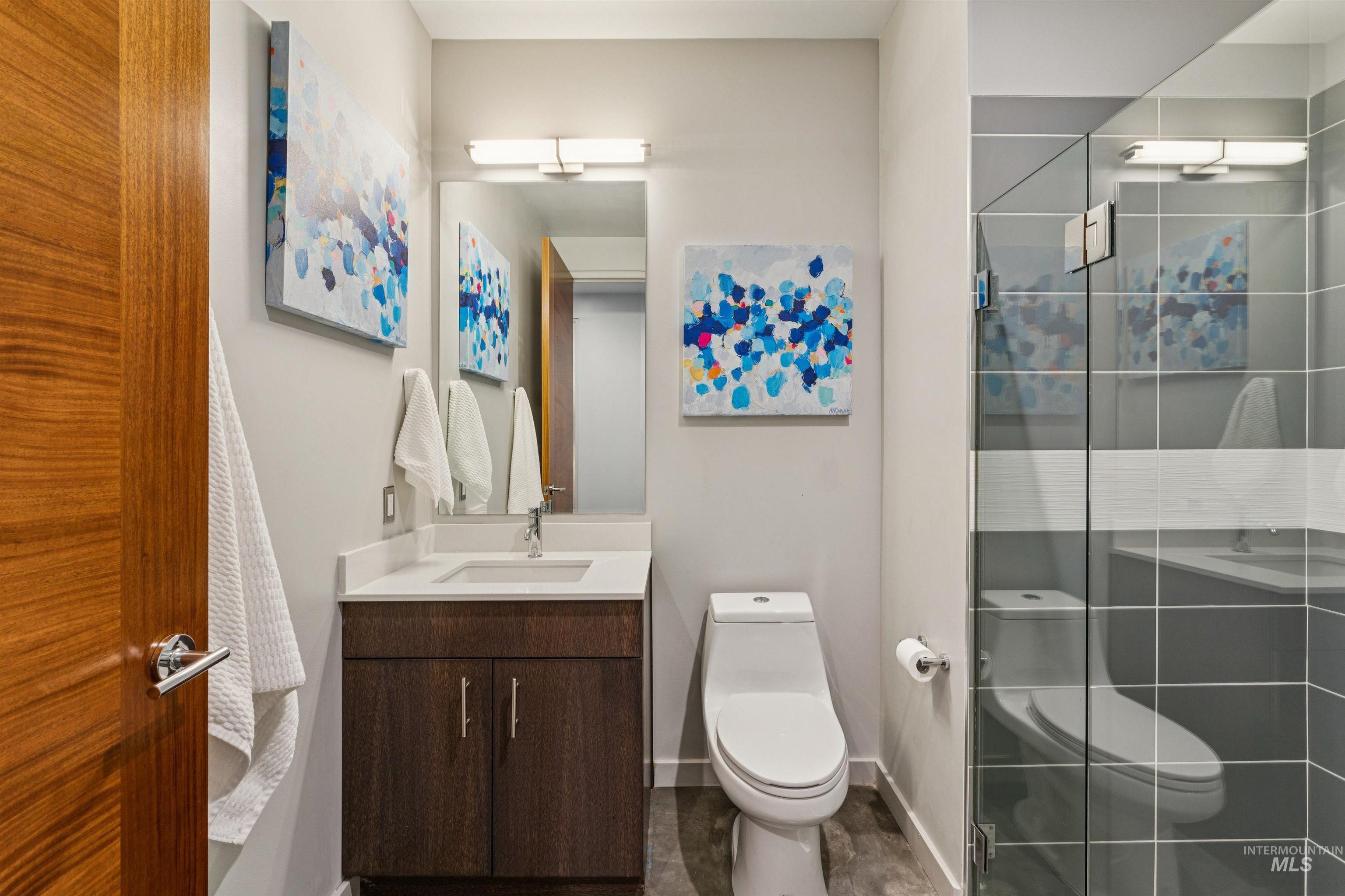 119 South 10th Street, Unit 307 Boise, ID 83702 - Photo 33 of 47 Bathroom featuring a dark wood-finish vanity with a white countertop and undermount sink, a sleek toilet, and a glass-enclosed shower with gray tiled walls