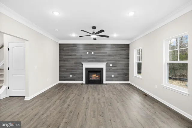 an empty room with wooden floor fireplace and windows