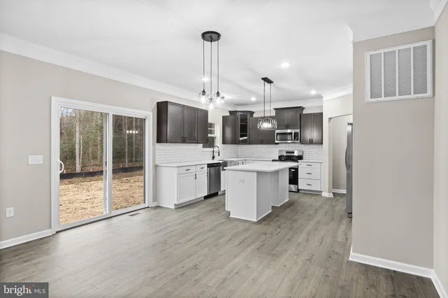 a kitchen with a sink stainless steel appliances cabinets and wooden floor