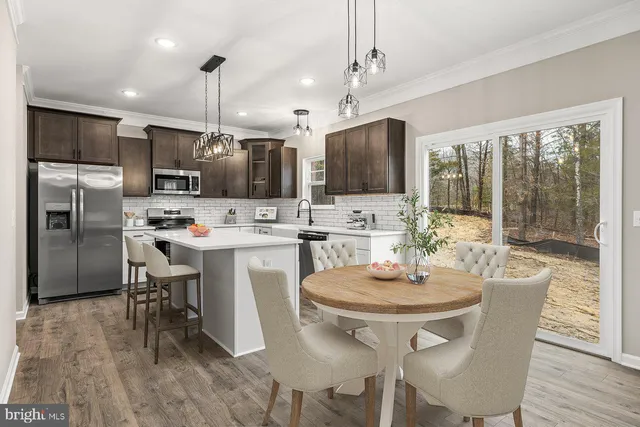 a kitchen with stainless steel appliances a dining table chairs stove refrigerator and microwave