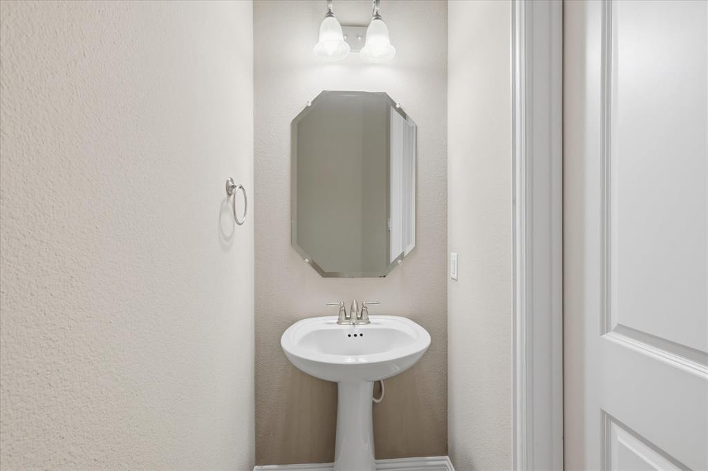 768 Huntingdon Street Coppell, TX 75019 - Photo 17 of 37 Convenient powder bath with pedestal sink, neutral finishes, and bright vanity lighting — perfect for guests.