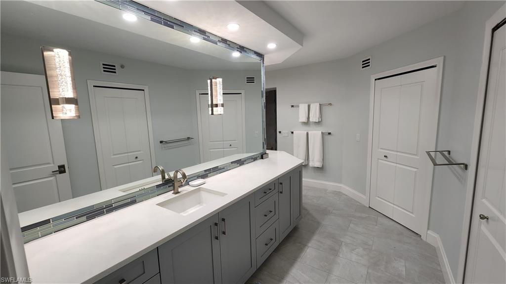 20 Seagate Drive, Unit 301 Naples, FL 34103 - Photo 13 of 29 a bathroom with a double vanity sink and mirror
