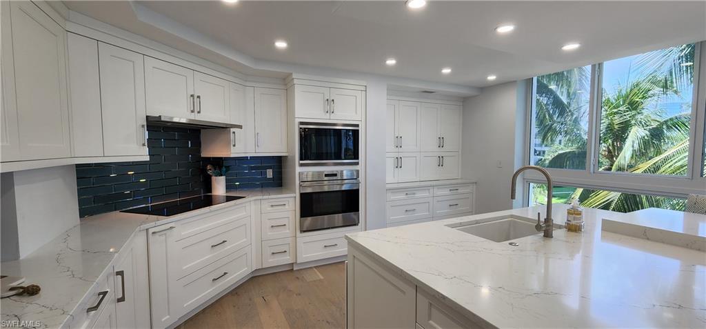 20 Seagate Drive, Unit 301 Naples, FL 34103 - Photo 6 of 29 a kitchen with white cabinets and black stainless steel appliances