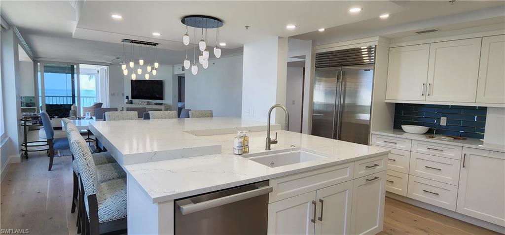 20 Seagate Drive, Unit 301 Naples, FL 34103 - Photo 7 of 29 a kitchen with white cabinets and stainless steel appliances