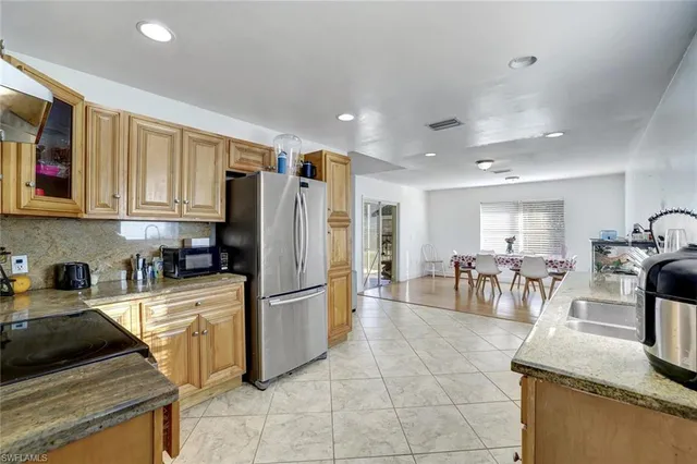 a kitchen with stainless steel appliances granite countertop a refrigerator a stove a sink a dining table and chairs with the cabinets