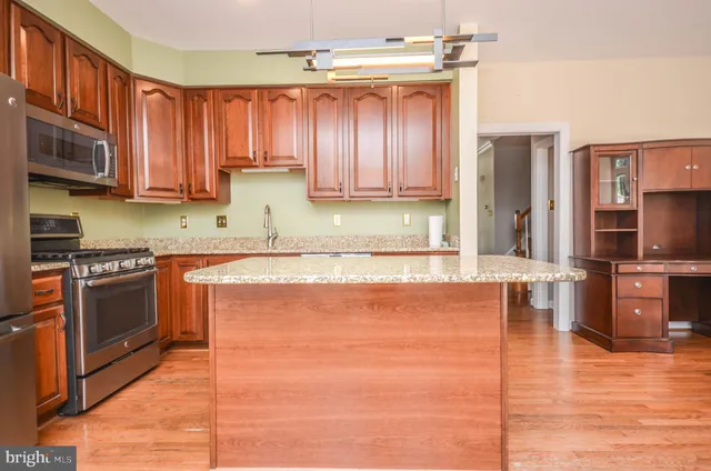a kitchen with stainless steel appliances granite countertop a refrigerator oven a sink dishwasher and wooden cabinets with a granite countertops