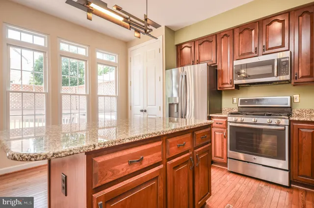 a kitchen with stainless steel appliances granite countertop a refrigerator a sink dishwasher and wooden cabinets with wooden floor