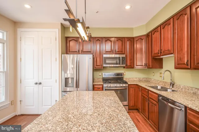 a kitchen with stainless steel appliances granite countertop a stove a sink dishwasher and a microwave oven with cabinets