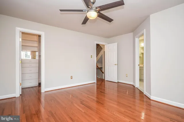 an empty room with wooden floor chandelier fan and windows