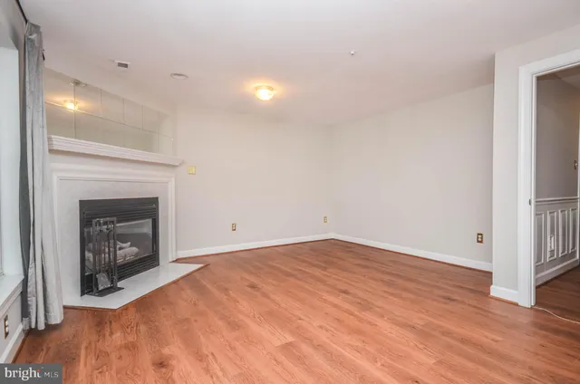 a view of empty room with wooden floor and fireplace