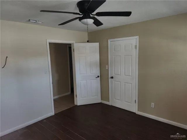 en empty room with wooden floor fan and a window