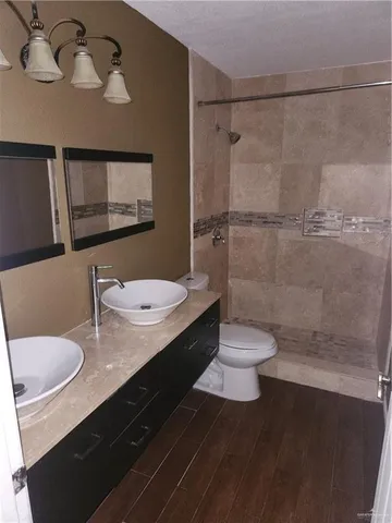 a bathroom with a sink a toilet a mirror and shower