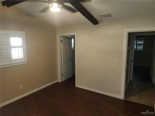 an empty room with wooden floor closet and windows