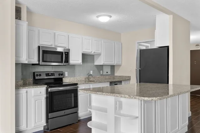 a kitchen with granite countertop white cabinets and stainless steel appliances