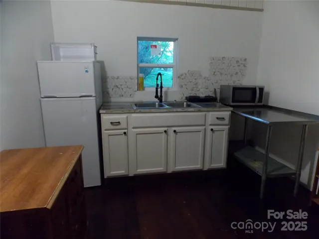 a kitchen with a sink a refrigerator and wooden floor