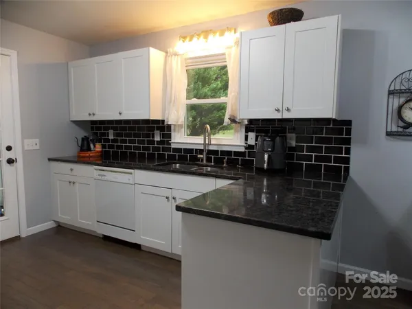 a kitchen with granite countertop a sink a window stainless steel appliances and cabinets