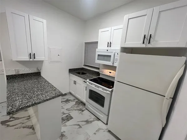 a kitchen with white cabinets and white appliances