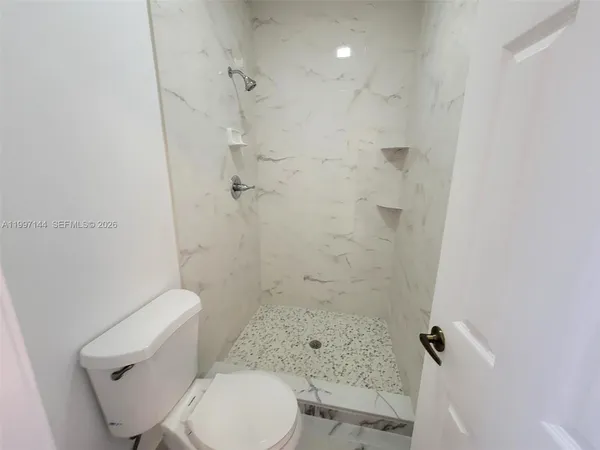 a white toilet sitting next to a bath tub shower