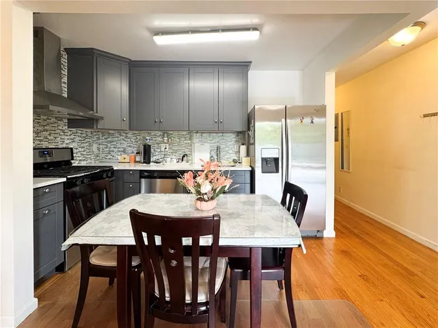 a kitchen with stainless steel appliances granite countertop a dining table chairs refrigerator and sink