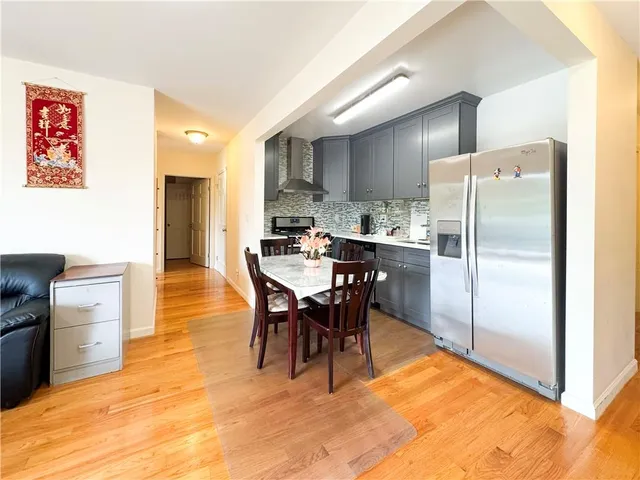 a kitchen with stainless steel appliances kitchen island granite countertop dining table chairs and a refrigerator