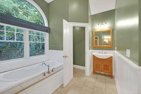 a bathroom with a tub sink and mirror