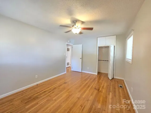 a view of empty room with wooden floor and fan