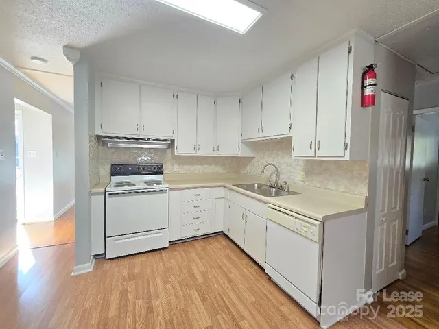 a kitchen with granite countertop white cabinets and white appliances