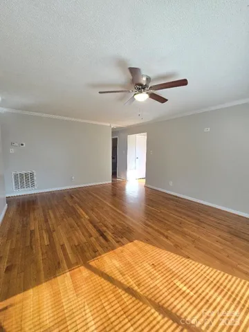 a view of a room with wooden floor and ceiling fan