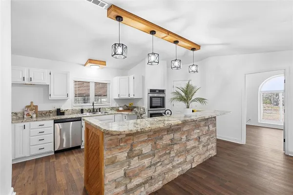 a kitchen with stainless steel appliances kitchen island granite countertop a stove a sink and a refrigerator