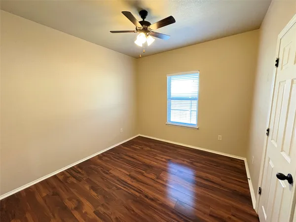 an empty room with wooden floor and a ceiling fan