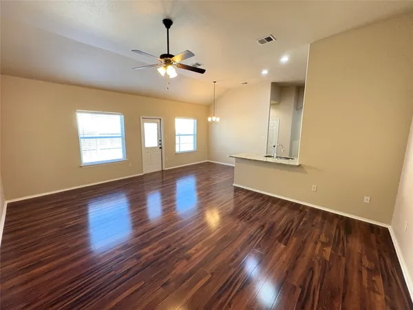 a view of an empty room with wooden floor and a window