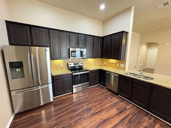 a kitchen with stainless steel appliances wooden cabinets a refrigerator a sink and a stove