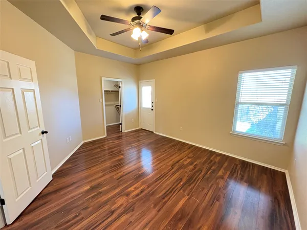 a view of empty room with wooden floor and fan