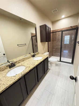 a bathroom with a granite countertop sink toilet and mirror